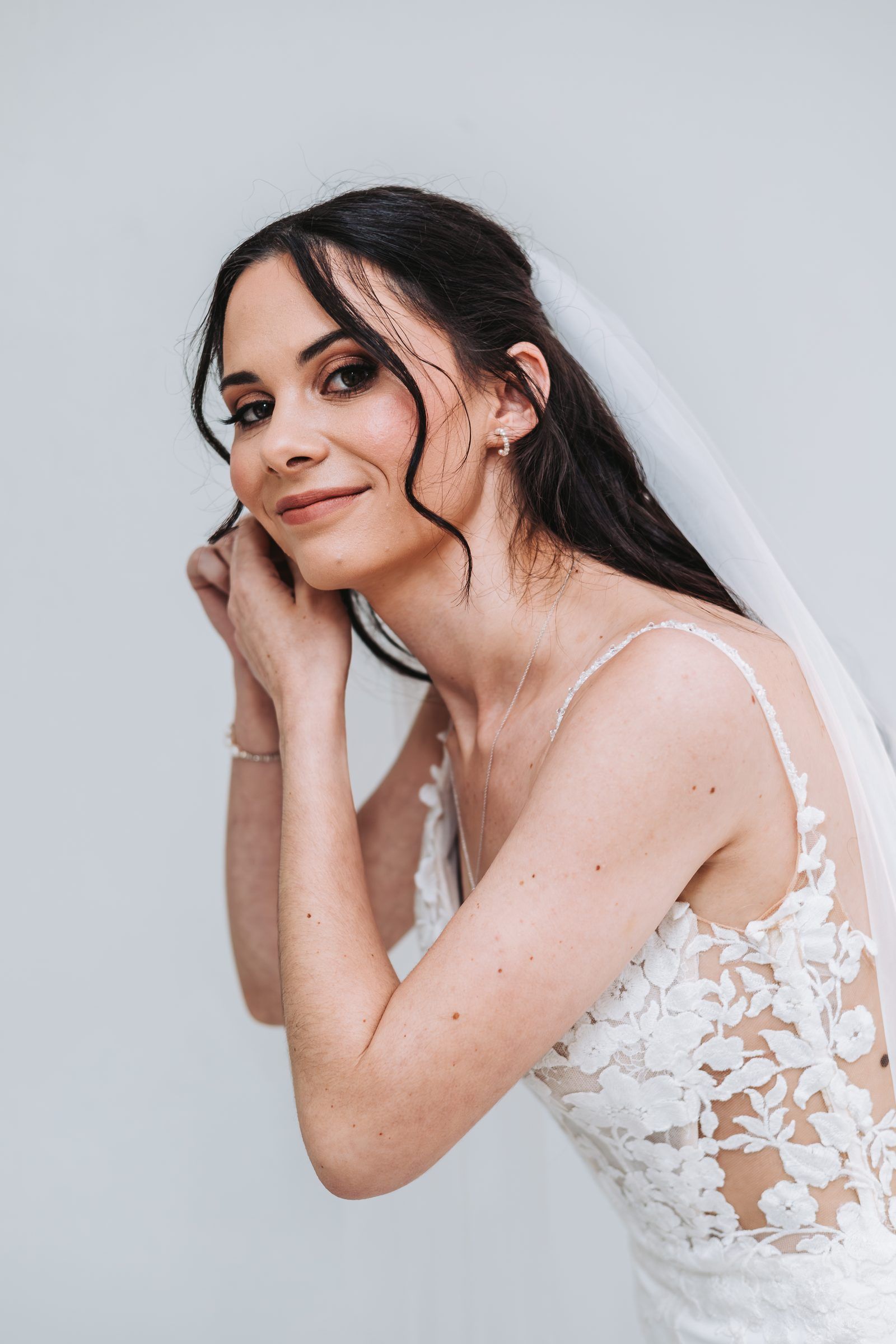 Bride in a lace gown and veil looking over her shoulder