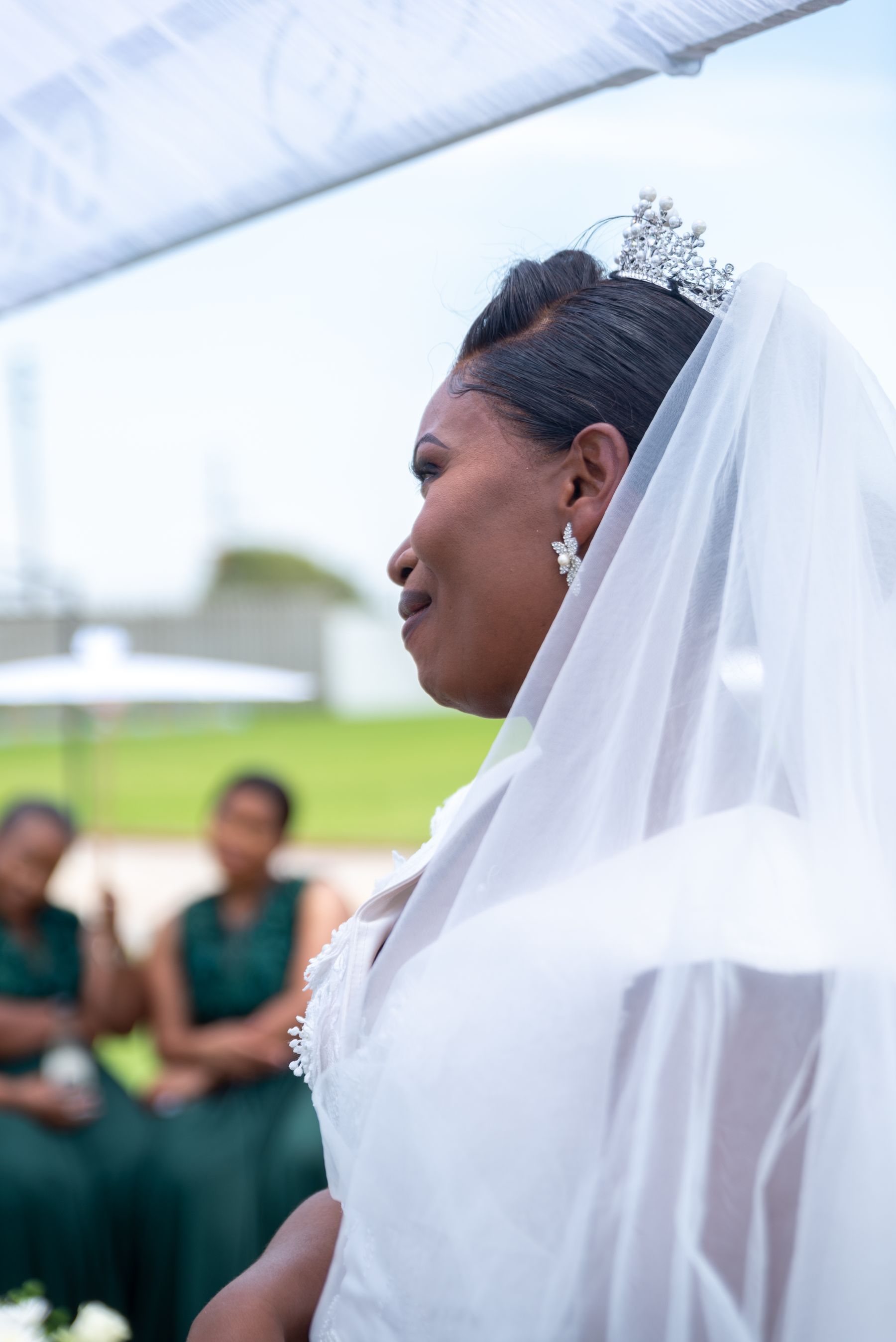 Bride in a lace veil smiling outdoors