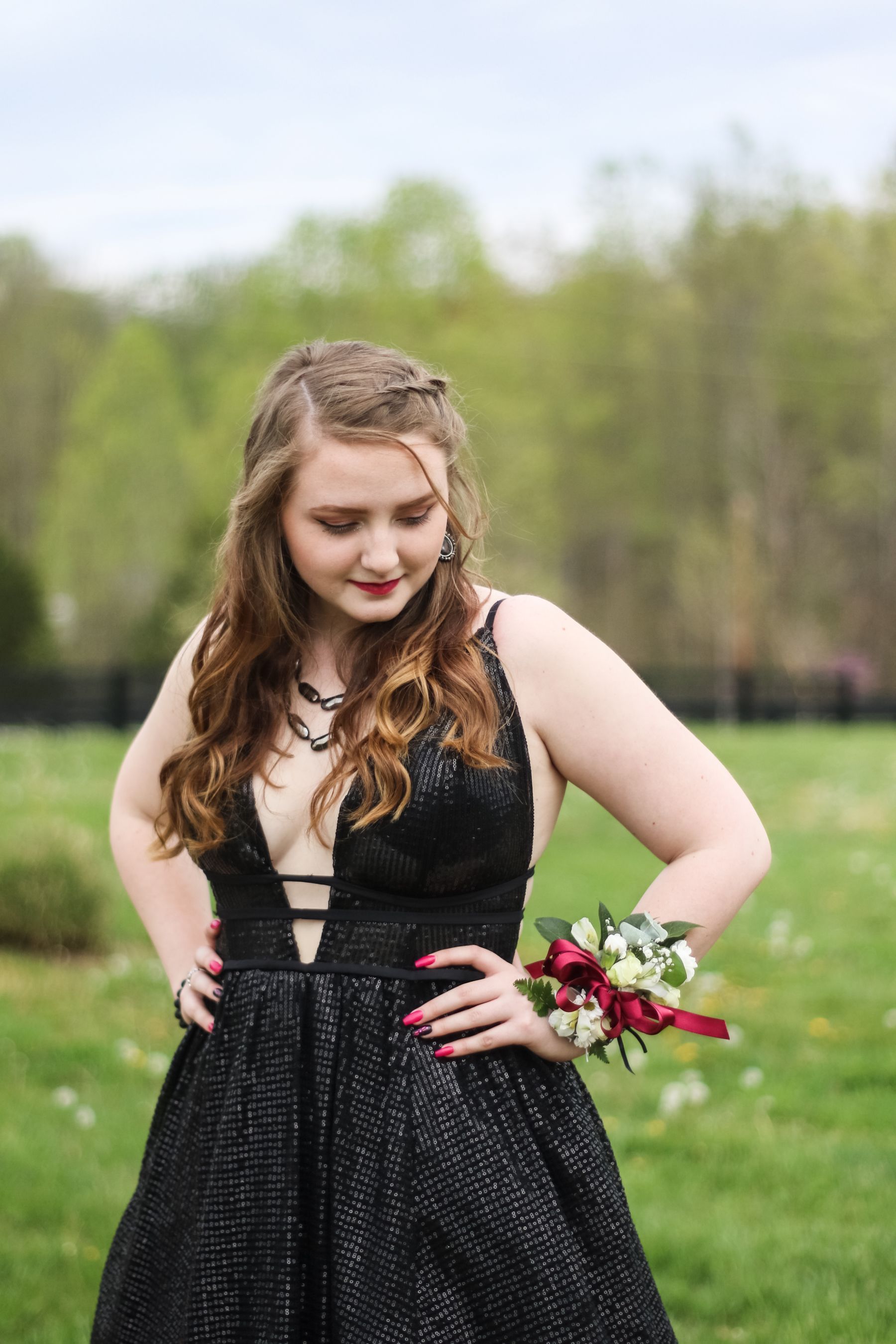 Young woman in a black gown with a wrist corsage on a lawn